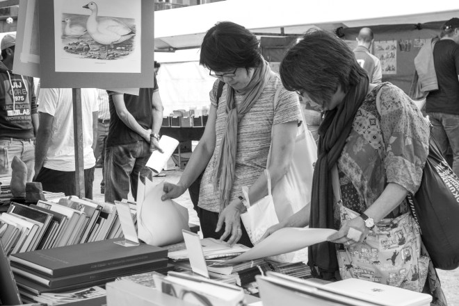 Two ladies comparing prints in a market book stall on the Dam in Amsterdam